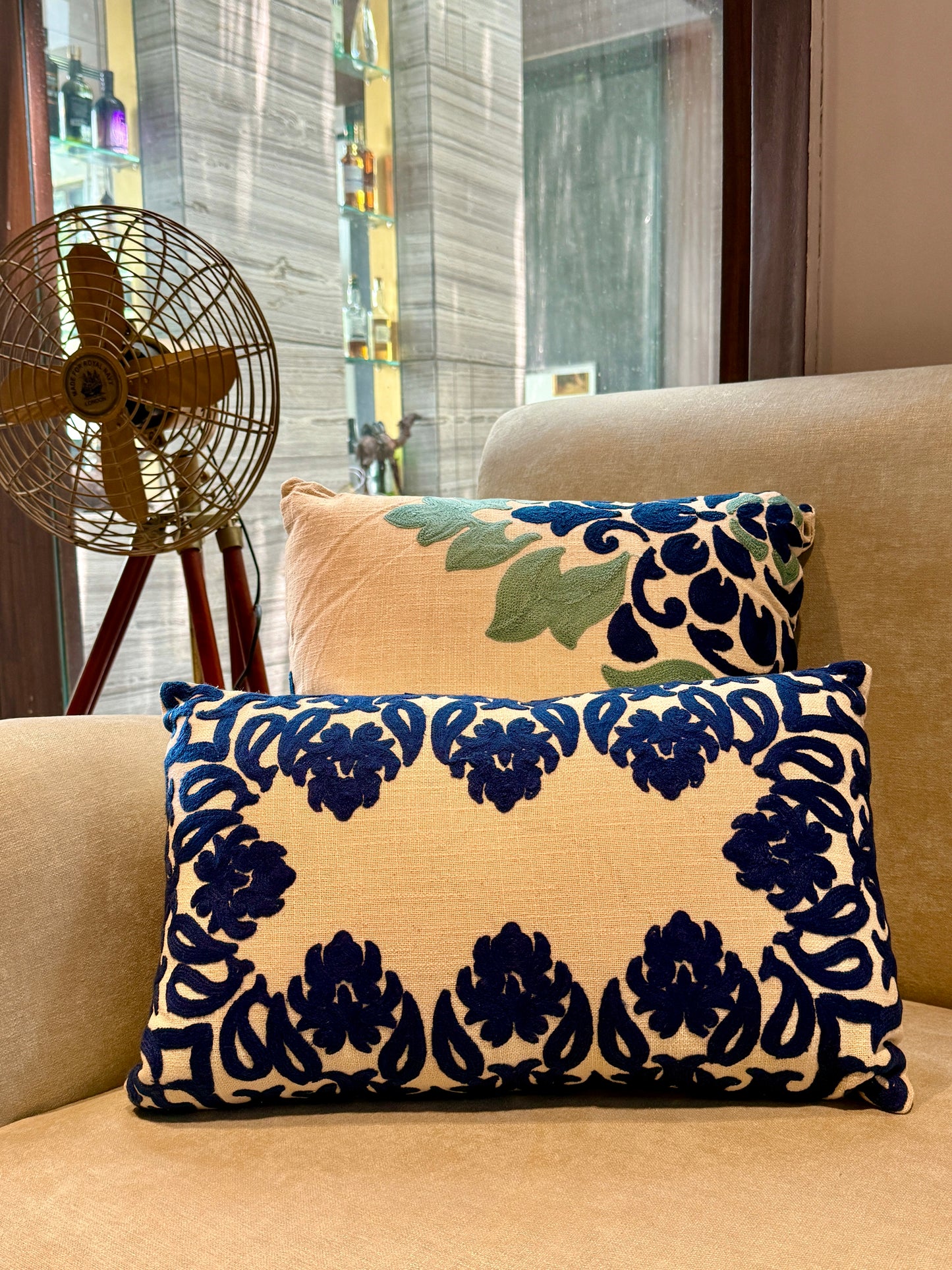 Featuring bold, hand-appliquéd floral and motif patterns in deep indigo on a natural beige cotton blend, its striking symmetry and rich texture add visual weight and elegance to beds, sofas, or accent chairs.