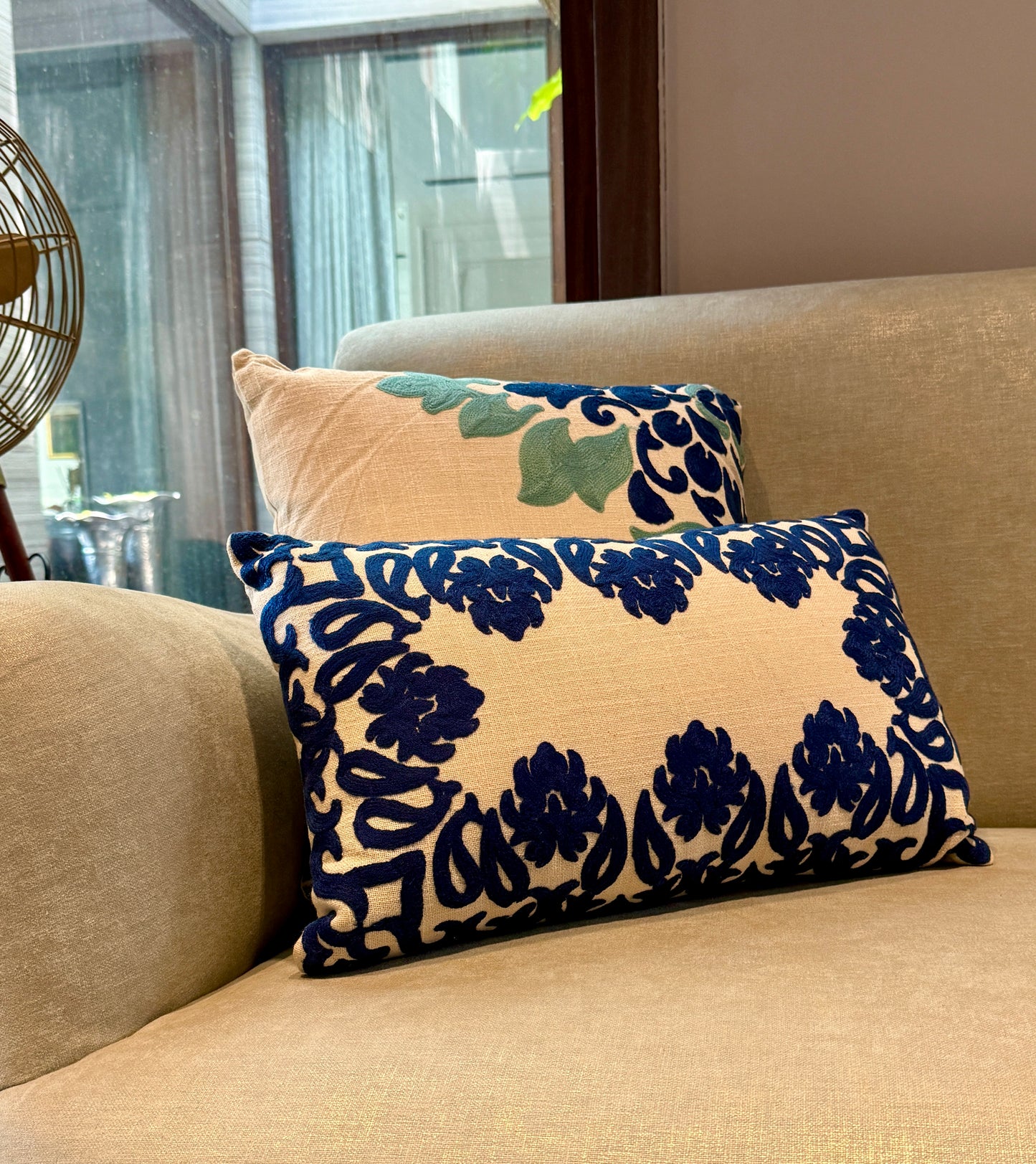Featuring bold, hand-appliquéd floral and motif patterns in deep indigo on a natural beige cotton blend, its striking symmetry and rich texture add visual weight and elegance to beds, sofas, or accent chairs.