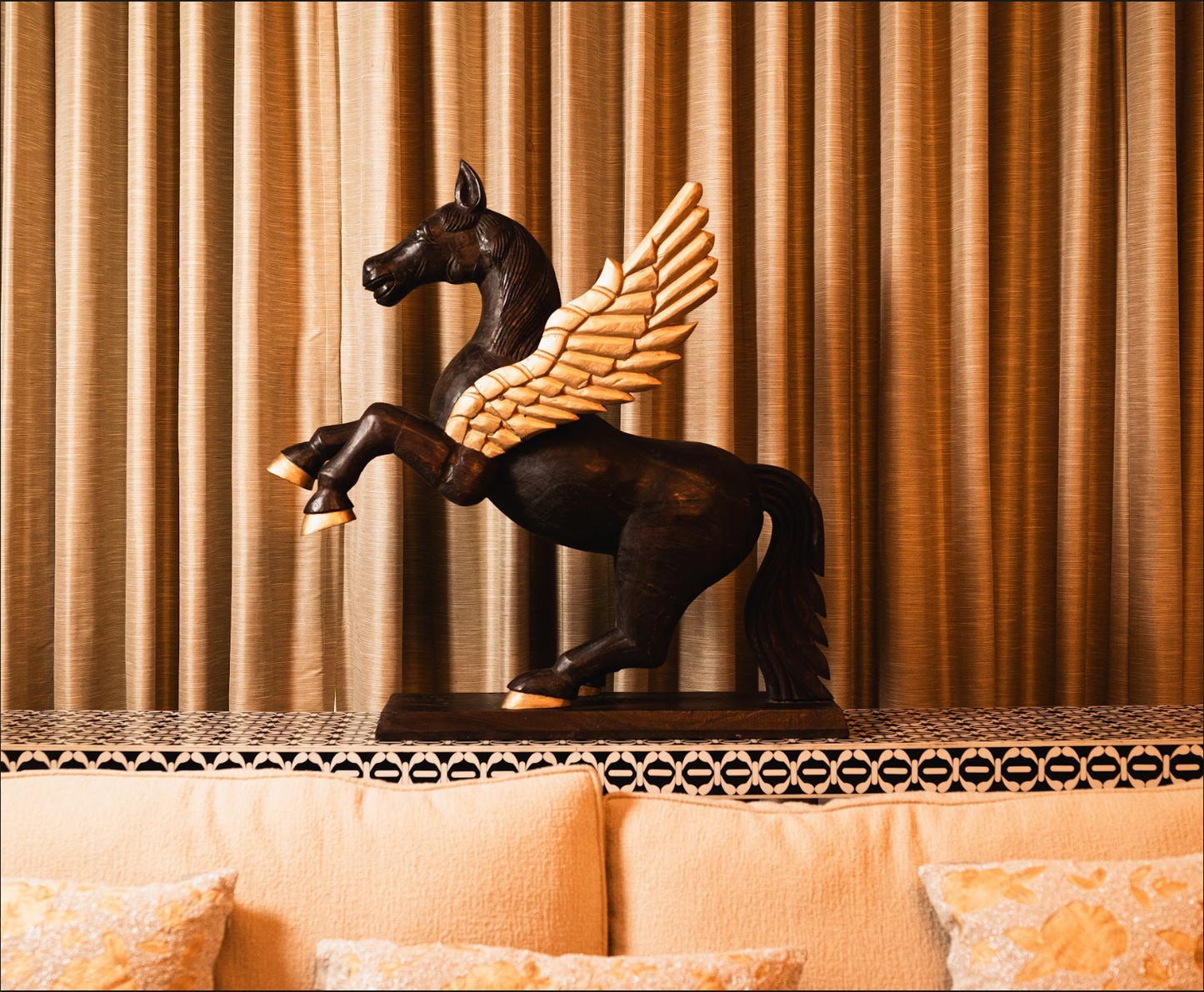 Channel the mythical charm of Pegasus into your home decor with this finely carved wooden sculpture. Expertly hand-painted, the majestic creature’s bold brown form is accentuated by elegant golden wings and hooves, creating a stunning contrast.