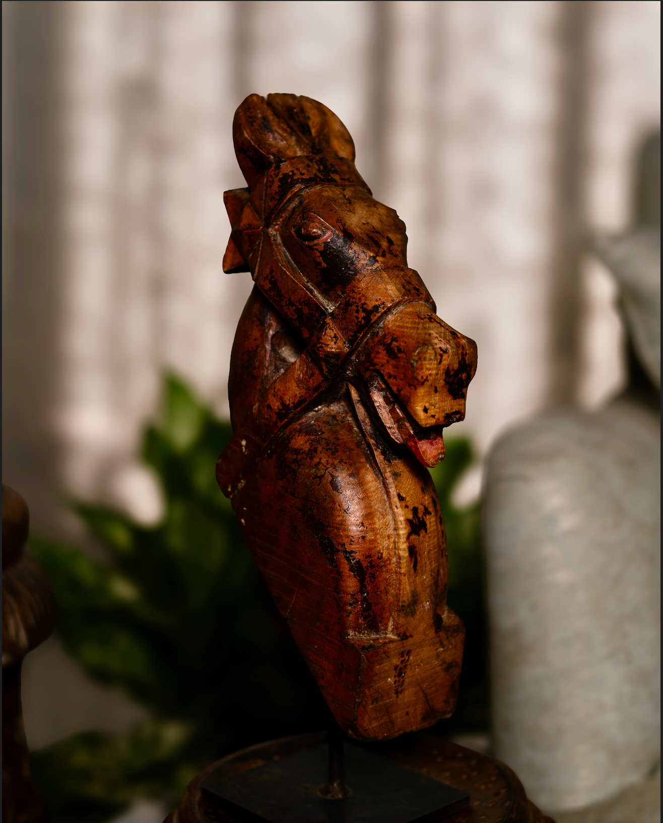 The Ashva Shilp is a hand-carved wooden horse head sculpture that embodies strength and vitality. With its natural orange patina and the striking detail of a pink-painted tongue, this salvaged fragment carries both character and charm.