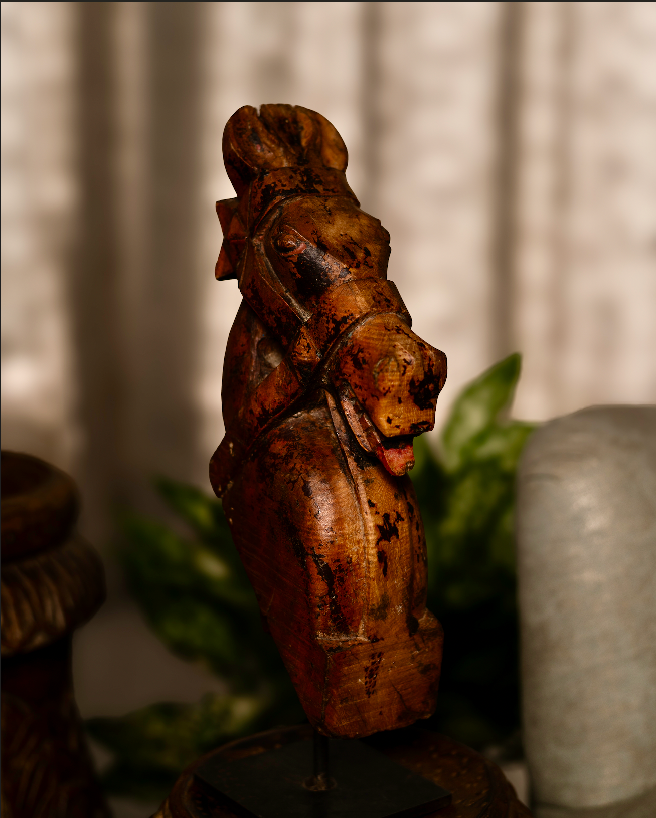 The Ashva Shilp is a hand-carved wooden horse head sculpture that embodies strength and vitality. With its natural orange patina and the striking detail of a pink-painted tongue, this salvaged fragment carries both character and charm.
