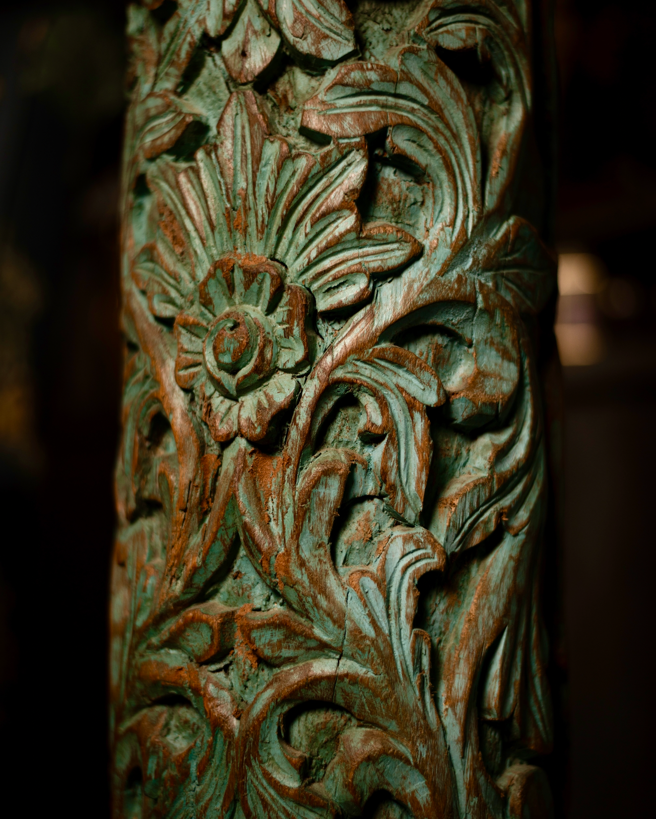 The Pushpa Stambh is a grand wooden pillar that carries the elegance of hand-carved floral motifs, flowing across its tall frame like a garden in bloom. Its natural greenish-blue patina, derived from plant-based pigments, enhances the depth of each carving while adding a soft vintage character.