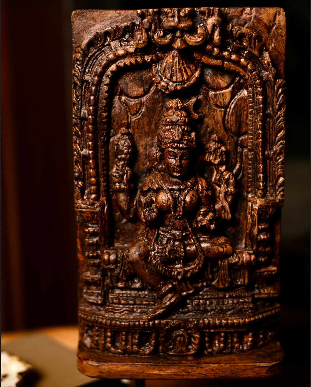 The Devālay Shilp Wooden Temple Panel carries the grace of sacred Indian artistry. Hand-carved from reclaimed wood, it depicts a richly detailed, the deity Laxmi, framed within ornate temple arches.