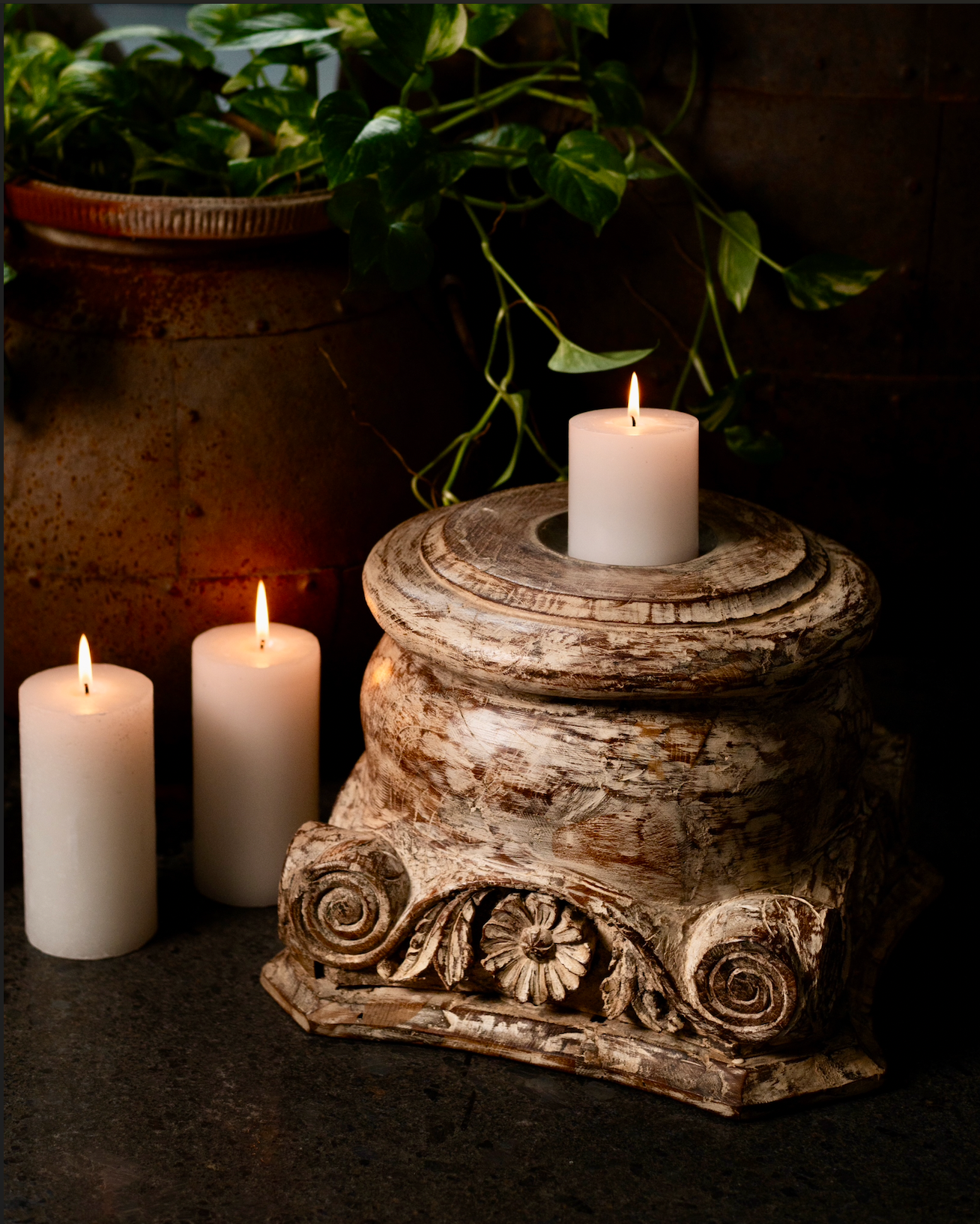 The Akriti Stambh Candle Pedestal, its detailed scrolls and pillar-inspired silhouette give it a timeless architectural charm, while the raw, unfinished surface highlights the natural character of the wood