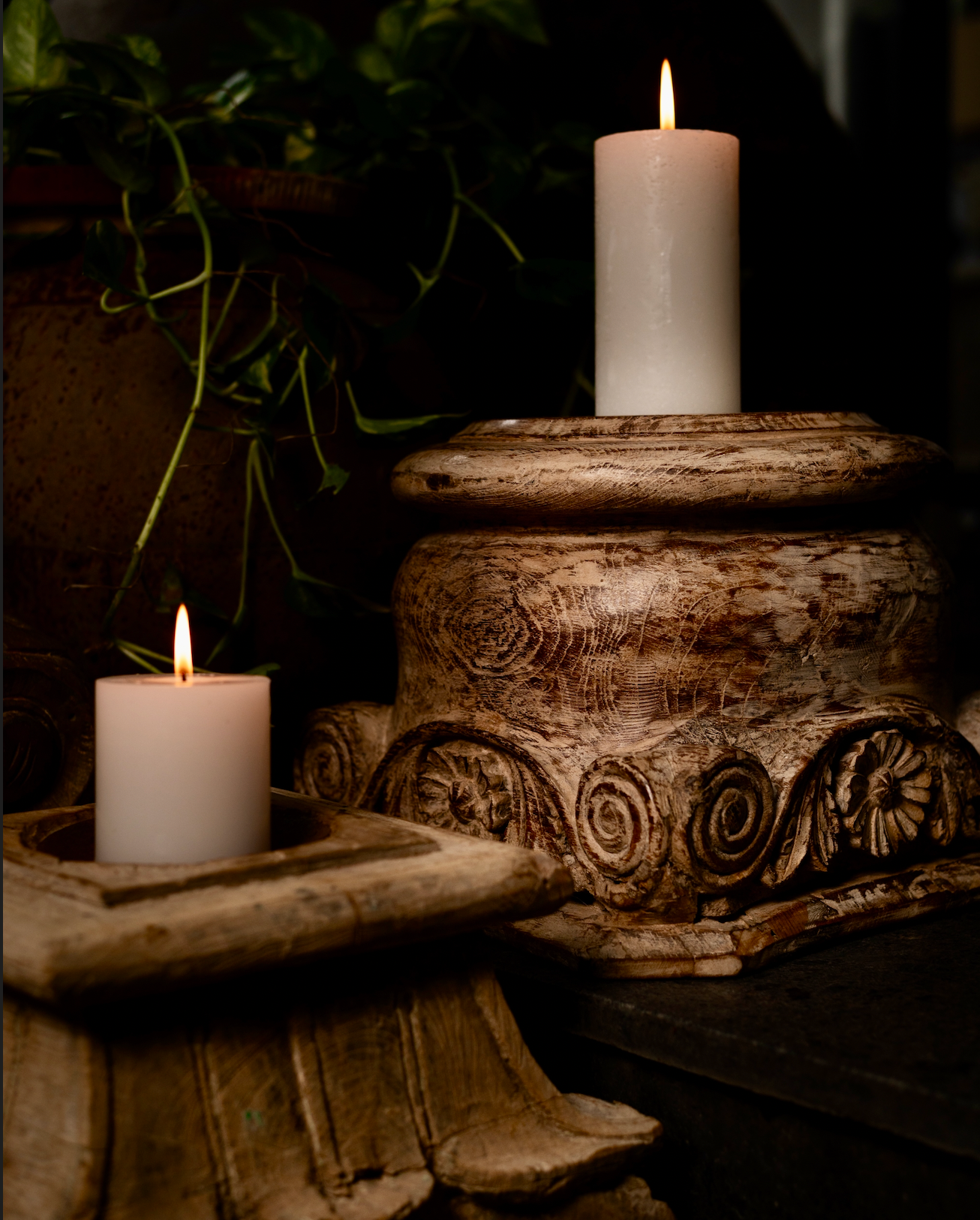 The Akriti Stambh Candle Pedestal, its detailed scrolls and pillar-inspired silhouette give it a timeless architectural charm, while the raw, unfinished surface highlights the natural character of the wood