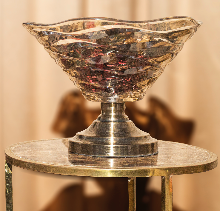 A glass decorative bowl made with crinkled glass supported by a metal stand.
