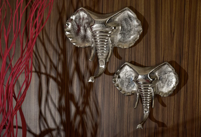A Set of 2 wall home decor accessory in shape of elephant heads made of aluminium in a silver finish.