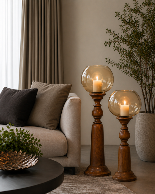 Turned wooden candle stands topped with hand-blown amber glass globes, designed to hold pillar candles at a graceful height. 