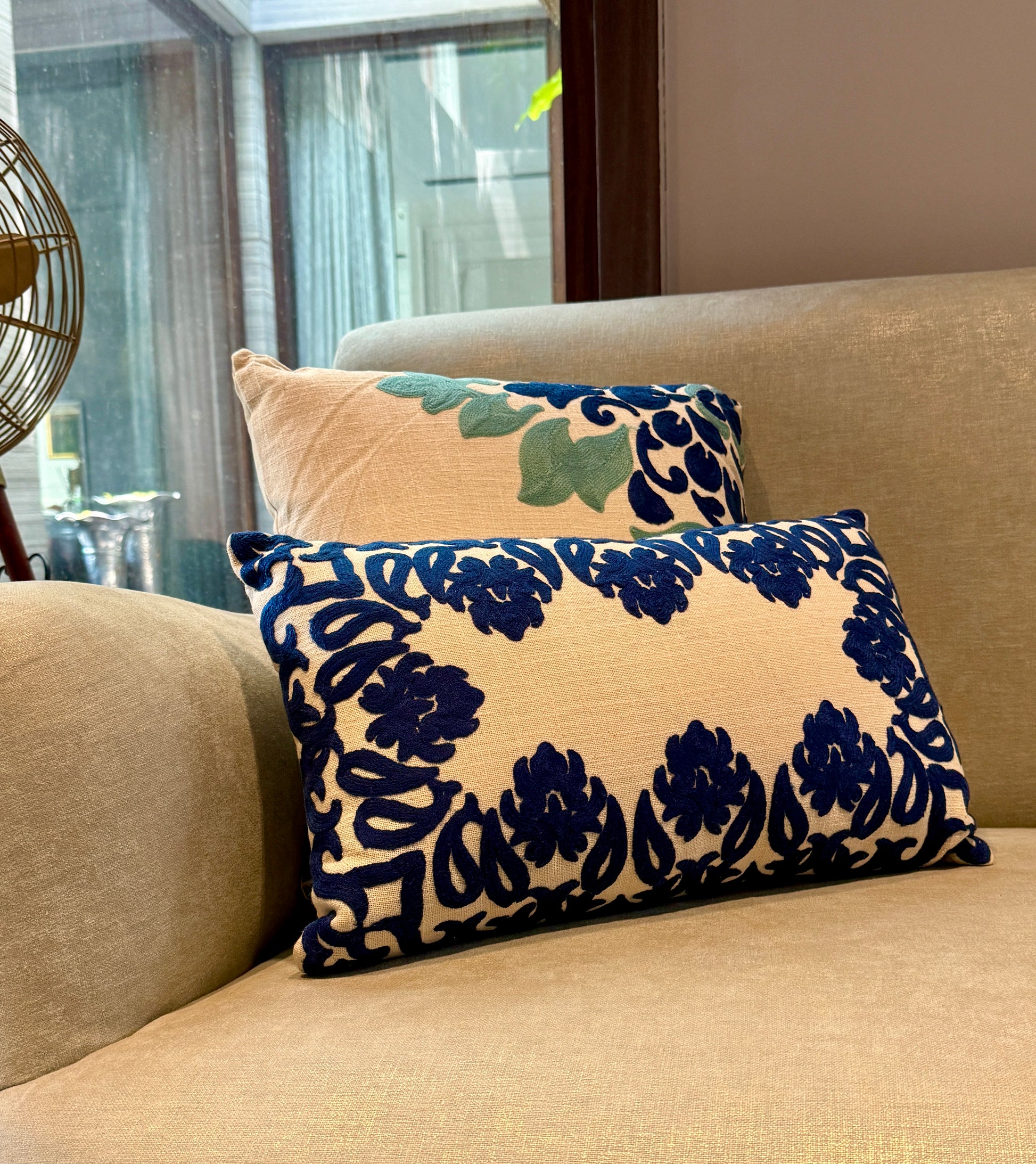 Featuring bold, hand-appliquéd floral and motif patterns in deep indigo on a natural beige cotton blend, its striking symmetry and rich texture add visual weight and elegance to beds, sofas, or accent chairs. 