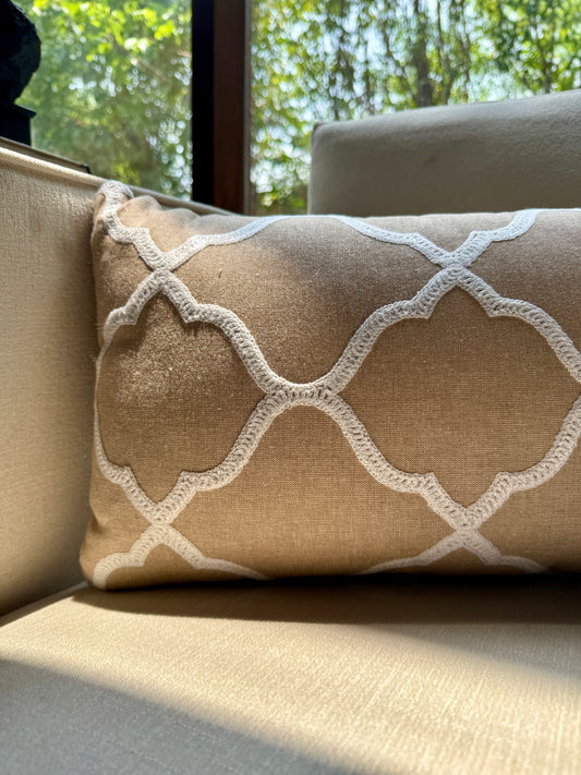 The Zahra Lattice Cushion features a classic Moroccan trellis pattern, delicately embroidered in ivory thread on a warm sand-toned base. 