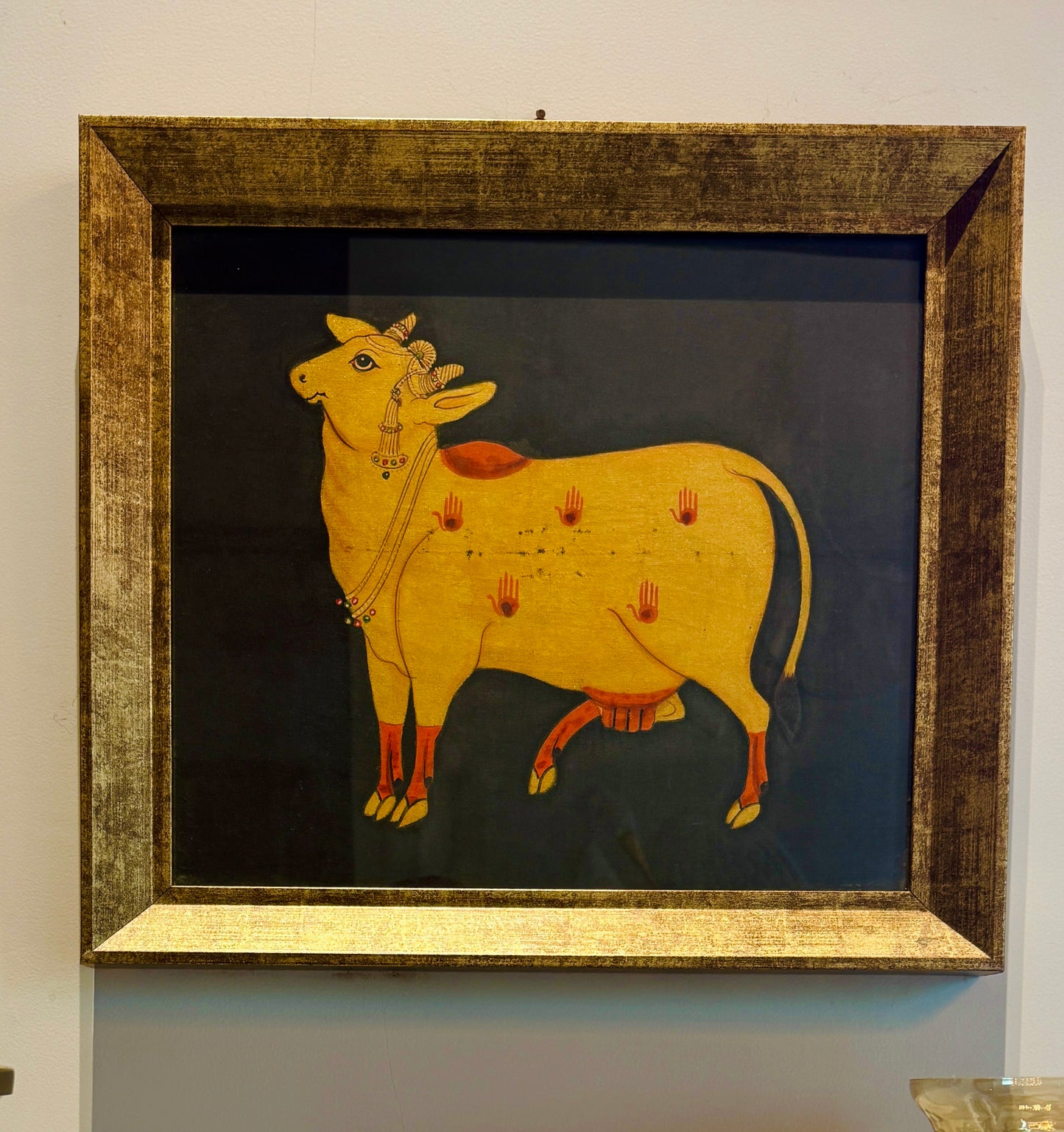 Hand-painted with real gold | Framed | Origin: Udaipur, Rajasthan This Udaipuri Pichvai captures Kamadhenu — the divine cow believed to grant all desires. Painted using natural pigments and real gold detailing, the artwork reflects the sacred richness of traditional temple murals. 