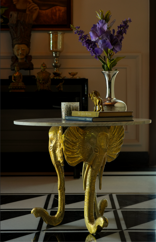 Our magnificent foyer table, a true testament to luxury and sophistication. Crafted with meticulous attention to detail, this extraordinary piece features a stand adorned with three majestic elephant faces, expertly crafted from aluminum and coated with a lustrous brass polish. 