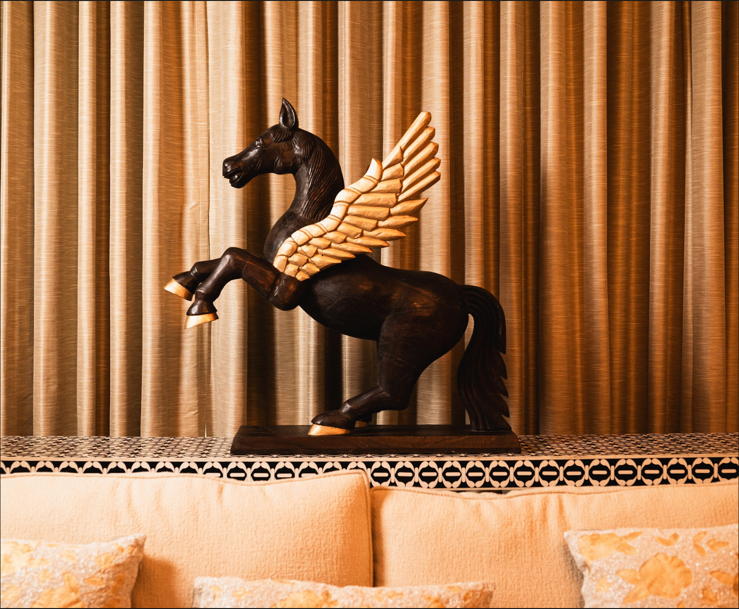 Channel the mythical charm of Pegasus into your home decor with this finely carved wooden sculpture. Expertly hand-painted, the majestic creature’s bold brown form is accentuated by elegant golden wings and hooves, creating a stunning contrast. 