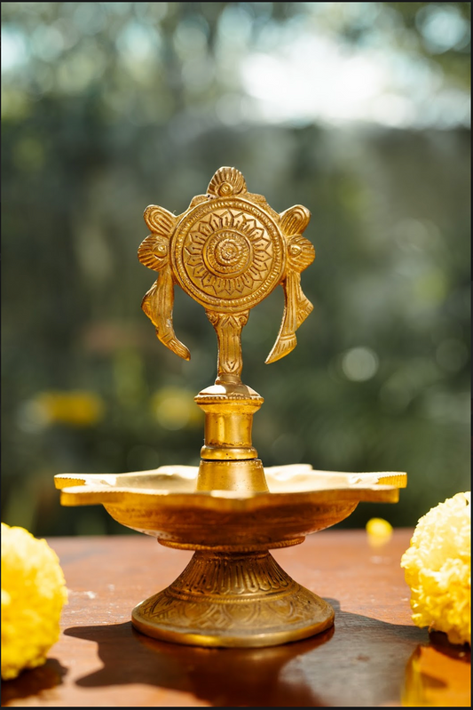 Expertly handcrafted, the diya features a detailed chakra (wheel) design, symbolizing the cycle of time, energy, and balance. Made from pure brass, this diya offers both aesthetic beauty and durability, making it perfect for pooja rituals, meditation spaces, or festive decor. 