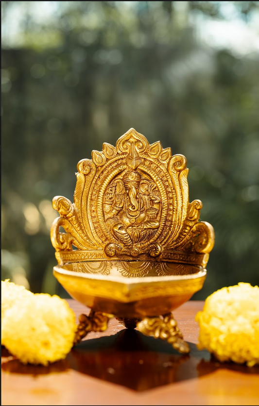 Handcrafted, this diya features a beautifully detailed Ganesh idol, symbolizing prosperity and wisdom. The intricate craftsmanship is evident in the fine details, from the deity’s form to the ornate carvings that surround the lamp.