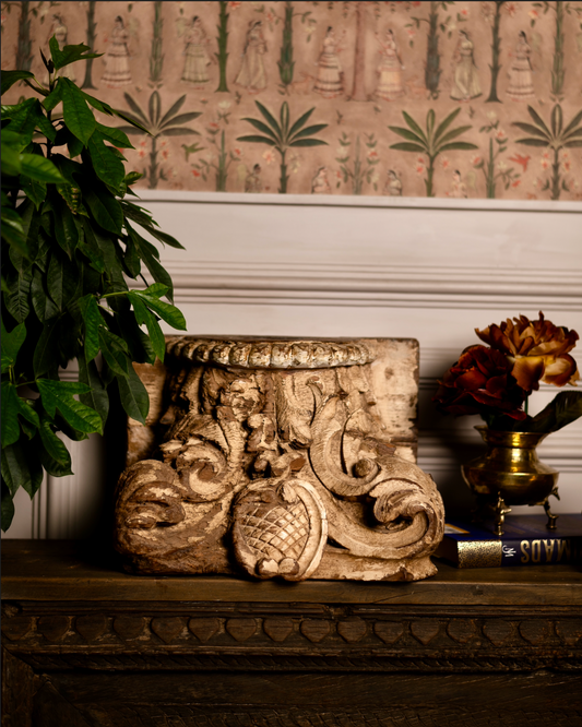 The Kusum Stambh Candle Pedestal is a stunning fragment of architectural heritage, hand-carved from solid reclaimed wood. With its ornate scrolls, floral accents, and natural distressed finish