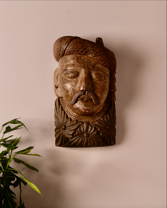 Carved from solid wood, the Veer Mukhā Wall Sculpture carries the regal presence of a bygone era. With its hand-detailed turban, mustache, and floral base, it reflects the strength and dignity of traditional Indian guardians often found in havelis and temples