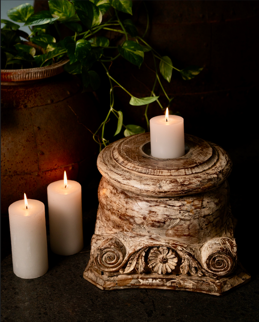 The Akriti Stambh Candle Pedestal, its detailed scrolls and pillar-inspired silhouette give it a timeless architectural charm, while the raw, unfinished surface highlights the natural character of the wood