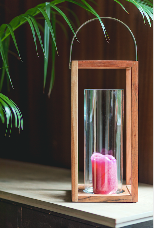 Structural wooden lanterns made of mango wood with a metal handle on top and a cylindrical glass candle holder within