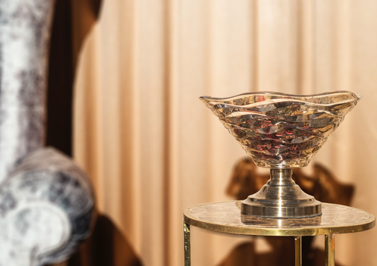 A glass decorative bowl made with crinkled glass supported by a metal stand.