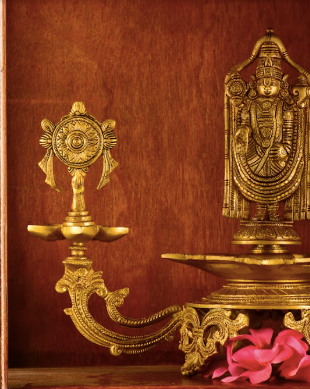 Brass Lord Tirupathi mounted atop a brass base with two diyas alongside each end.