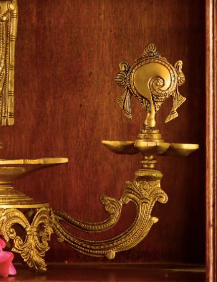 Brass Lord Tirupathi mounted atop a brass base with two diyas alongside each end.