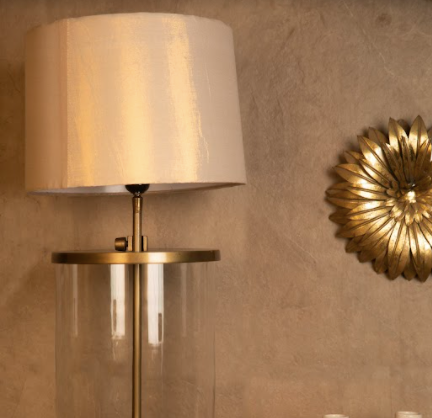 With the stem of the lamp made with metal and a glass cylinder wrapped around it, the lamp stands tall in an antique gold finish.