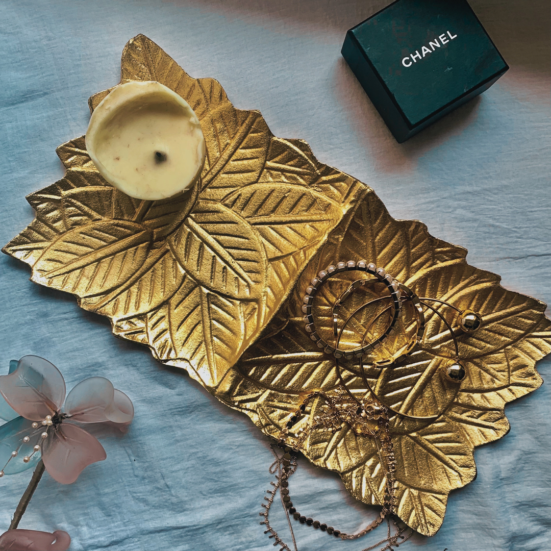 A gold tray with leaf accents enbedded into it 