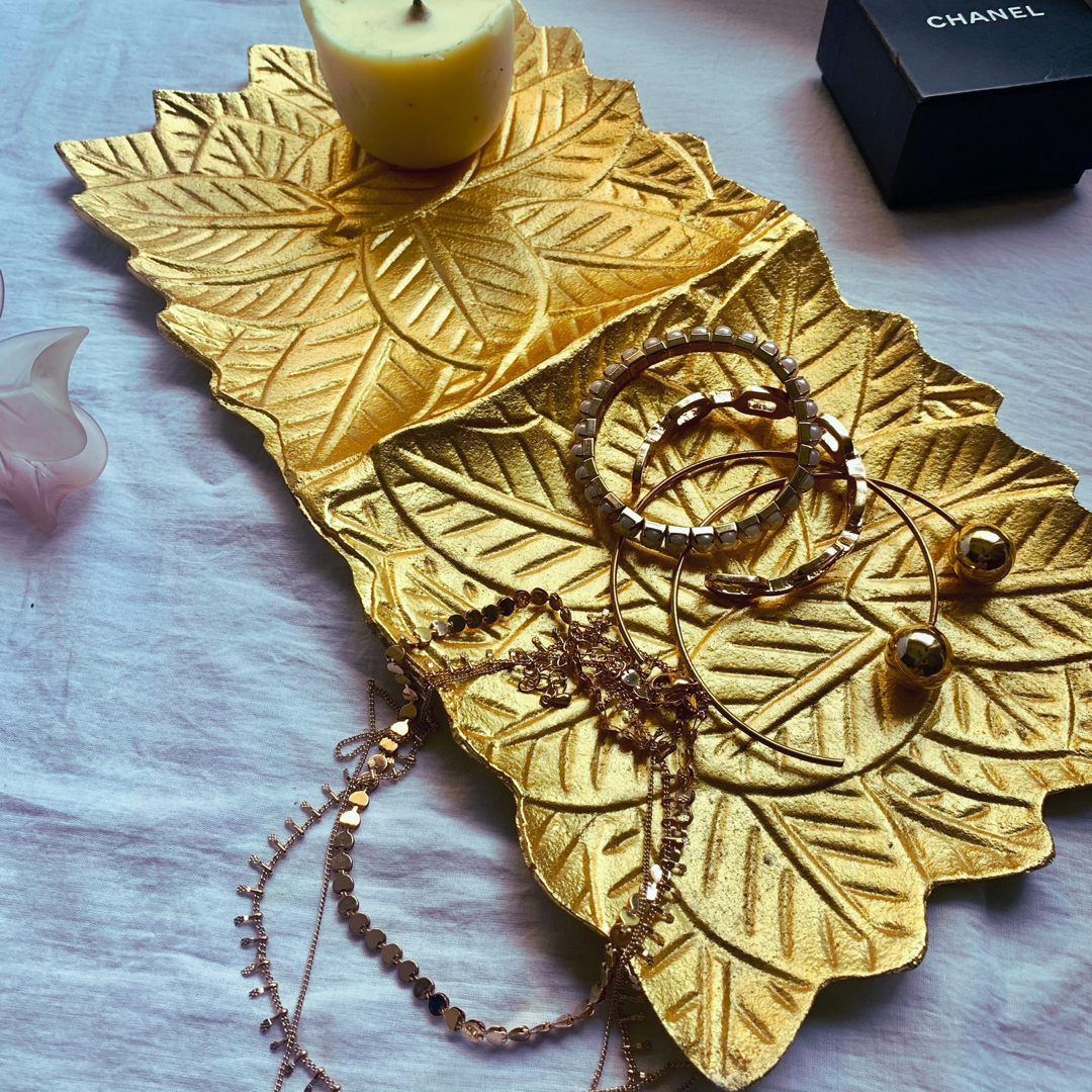A gold tray with leaf accents enbedded into it 